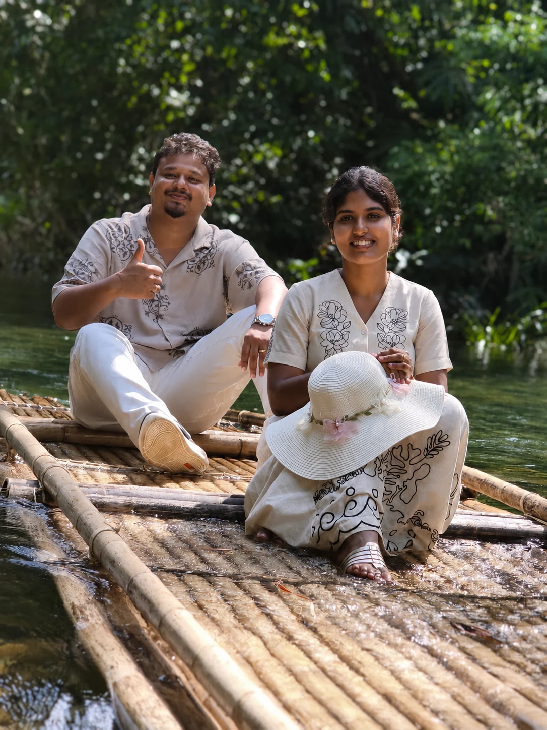 Two people on a bamboo raft surrounded by water and greenery